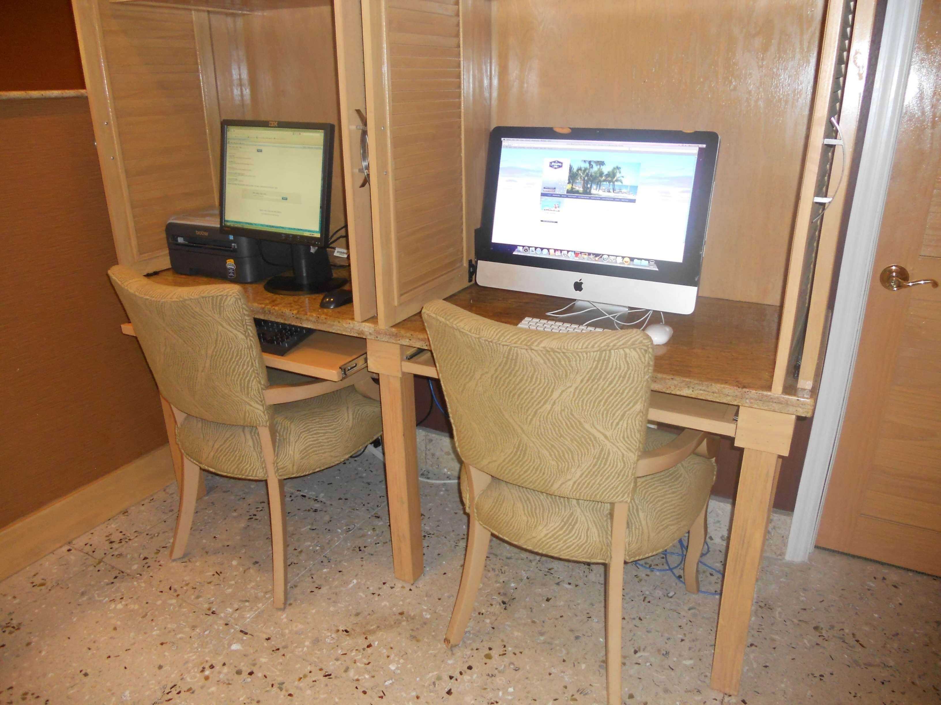 A small office space with two desks, each with a computer and a chair.
