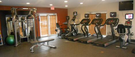 A gym with treadmills, elliptical machines, and weightlifting equipment.