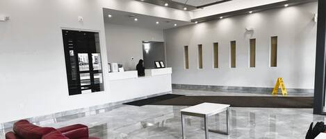 A modern lobby with a red leather sofa, a reception desk, and a clean, tiled floor.