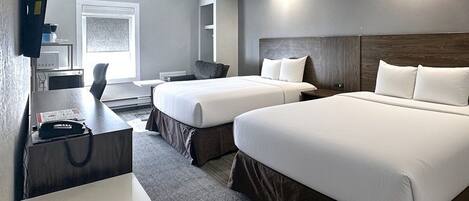 A hotel room with two beds, a desk, a chair, a TV, and a window.