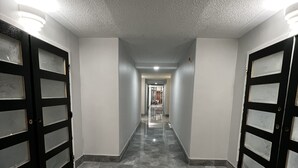 Un pasillo con suelo de baldosas y puertas dobles a ambos lados.