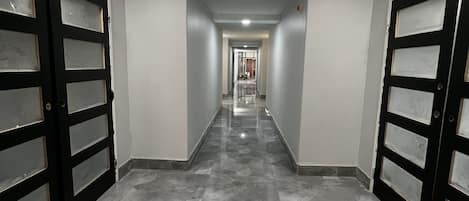Un couloir doté d’un sol carrelé et de portes à deux battants de chaque côté.