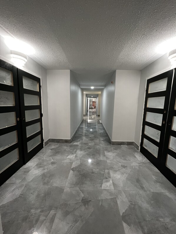 A hallway with a tiled floor and double doors on both sides.