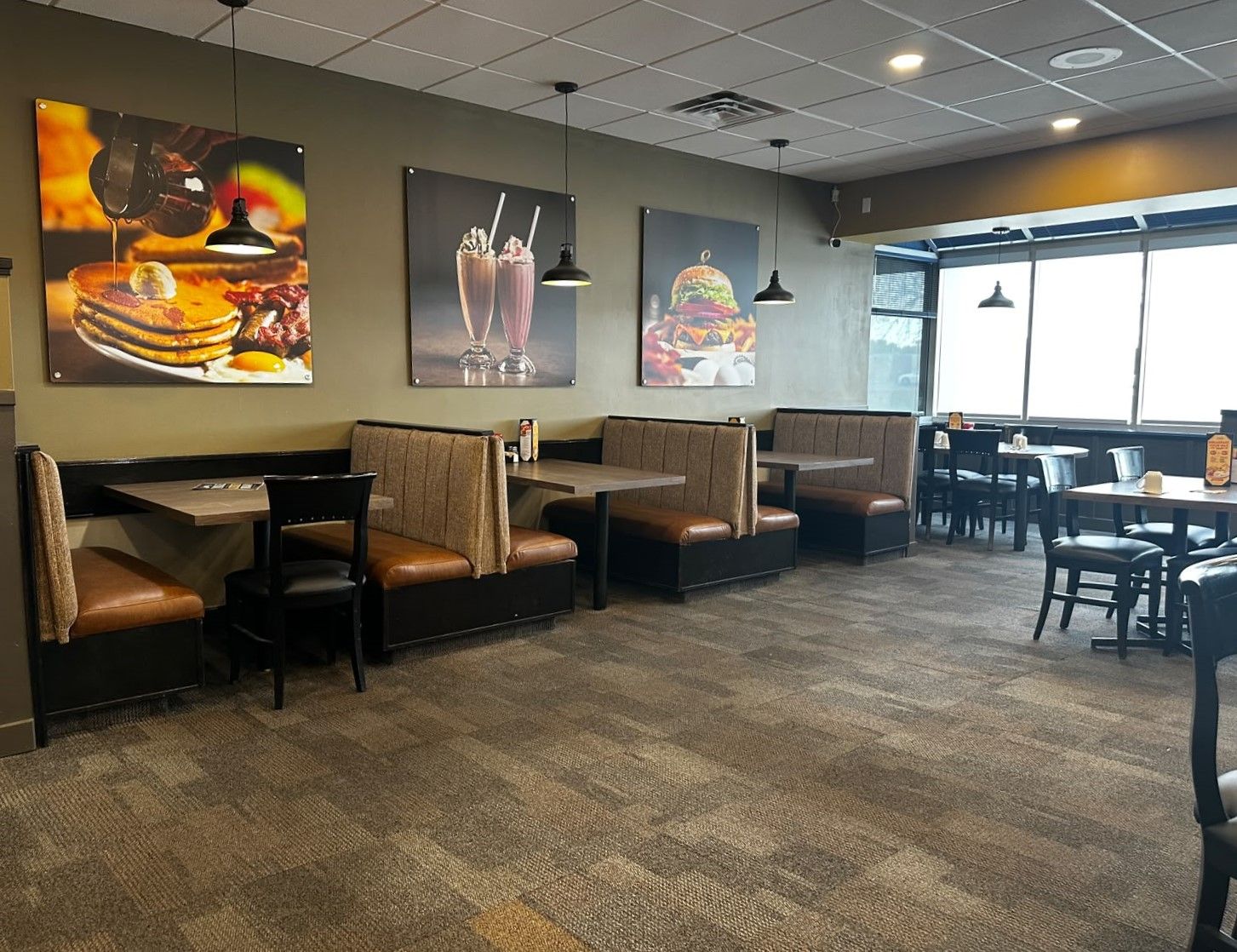 A restaurant interior with booth seating, high tables, and wall art depicting food.