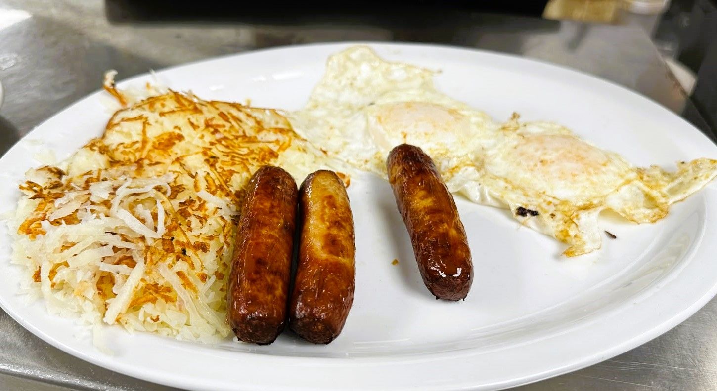 A plate with hash browns, two sausages, and a fried egg.