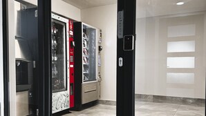 Un interior moderno con una máquina expendedora, una puerta de cristal y un suelo de baldosas.