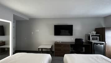 A hotel room with two beds, a desk, a chair, a flat-screen TV, a microwave, and a small refrigerator.