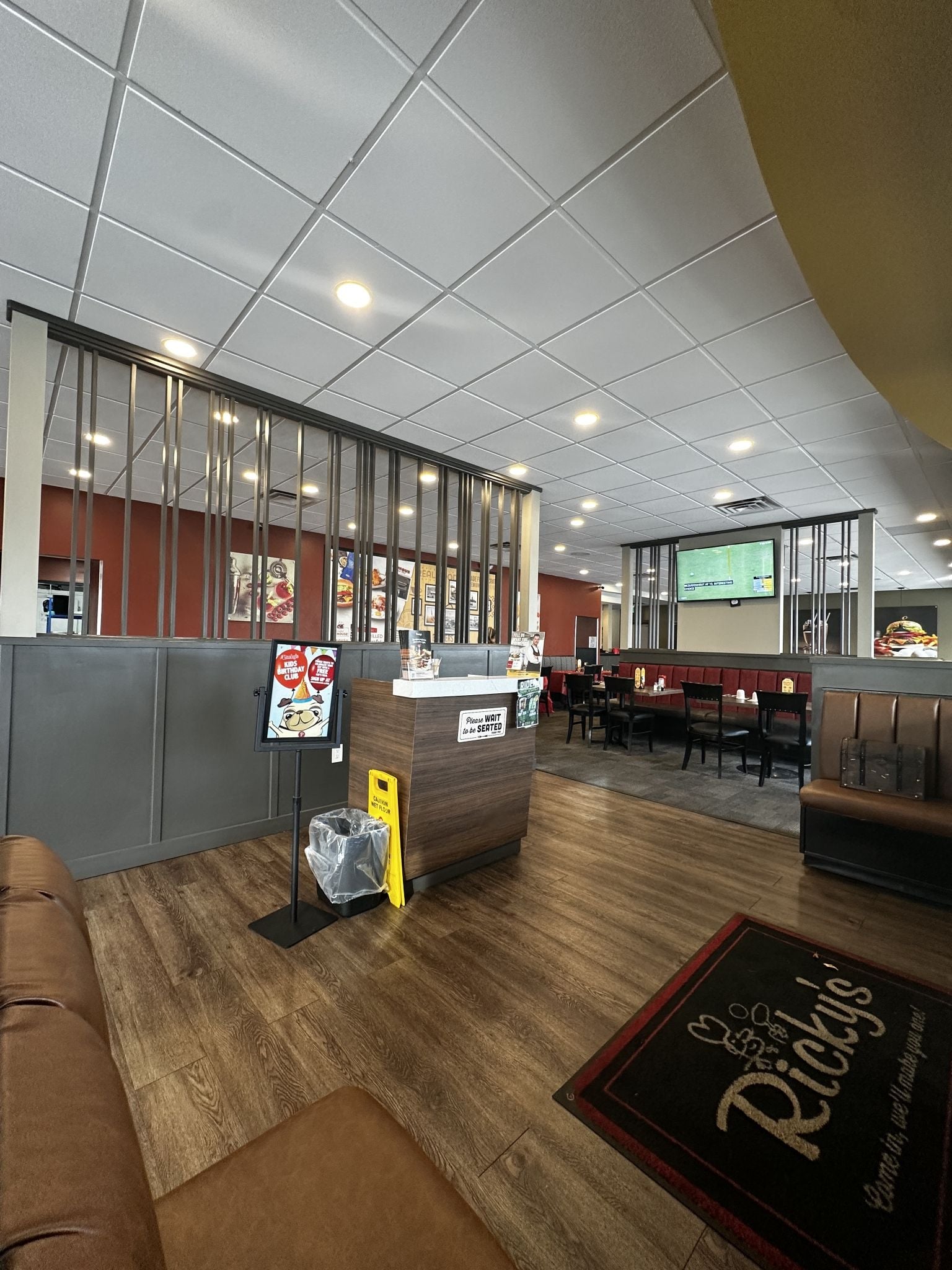 A restaurant interior with a counter, seating area, and a digital menu display.