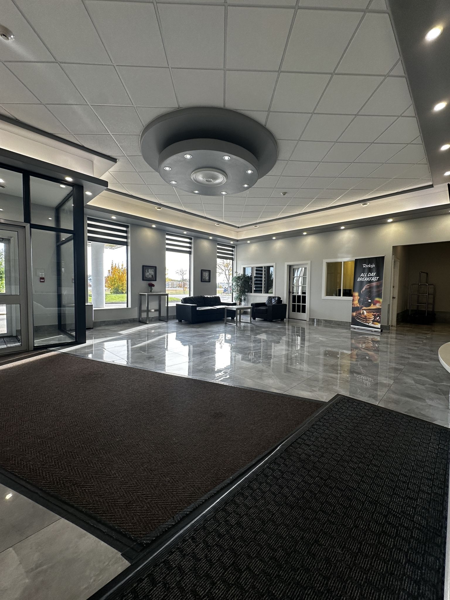A spacious lobby with a modern design, featuring a central seating area, large windows, and a clean, polished floor.