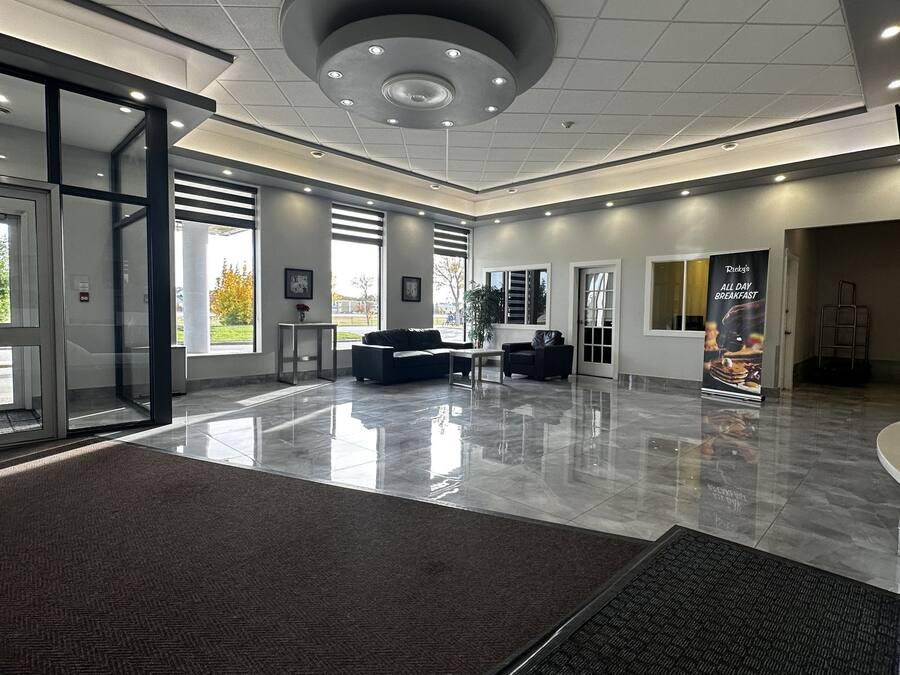 Un amplio vestíbulo con diseño moderno, que presenta una zona de estar central, ventanas grandes y un piso limpio y pulido.