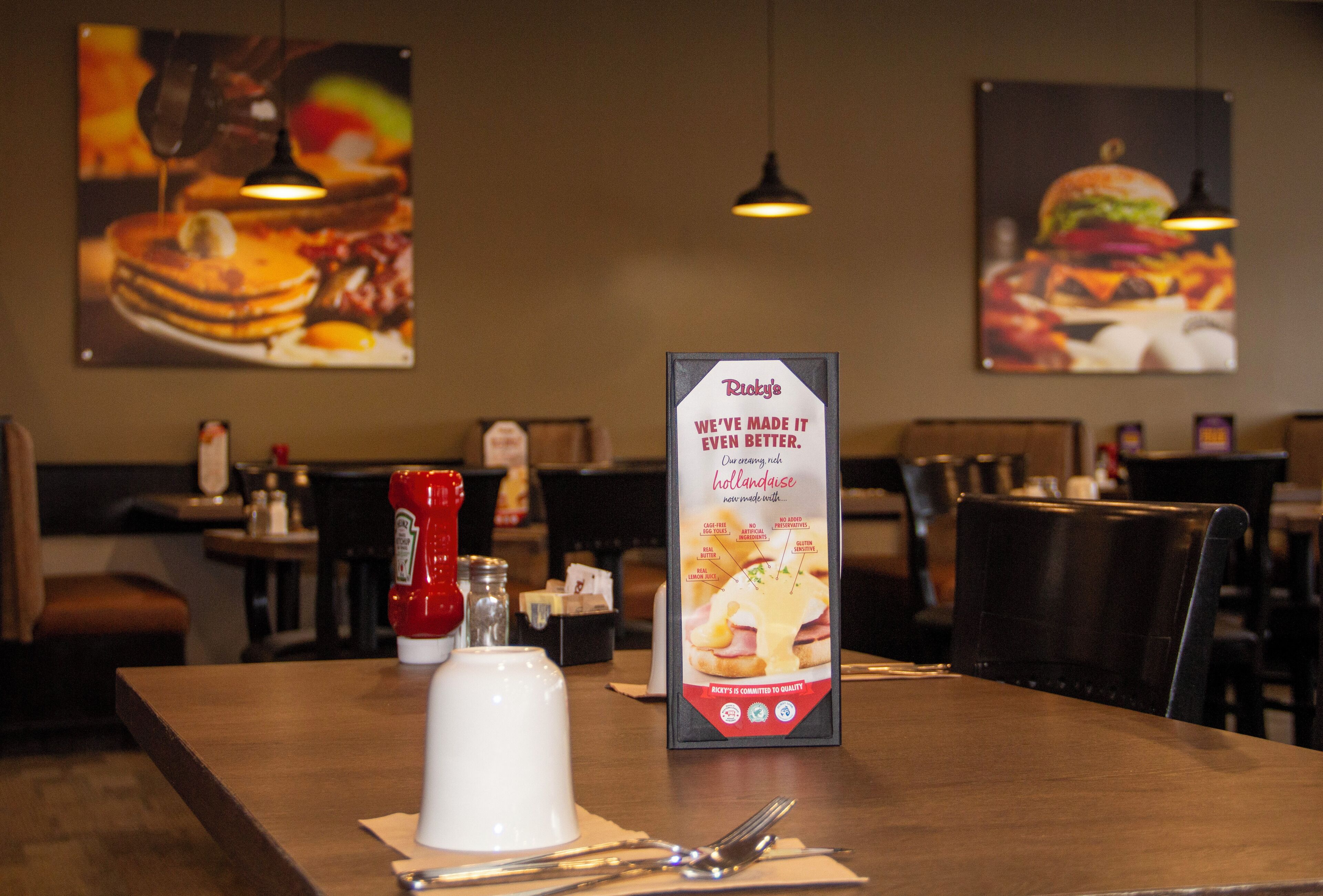 A restaurant interior with a menu board, condiments, and a clean dining table.