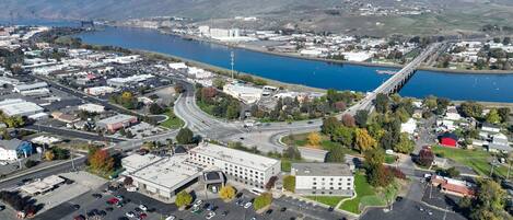 An aerial view of a town with a large parking lot, a bridge, and a body of water.