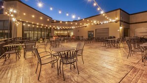 An outdoor patio area with tables and chairs, string lights, and a building in the background. - Hells Canyon Grand Hotel, an Ascend Collection Hotel (Lewiston)