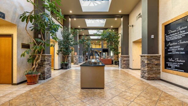 A spacious hotel lobby with a central island, potted plants, and a chalkboard menu on the wall. - Hells Canyon Grand Hotel, an Ascend Collection Hotel (Lewiston)