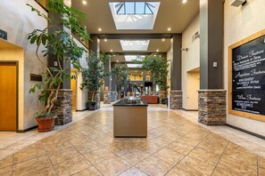 A spacious hotel lobby with a central island, potted plants, and a chalkboard menu on the wall. - Hells Canyon Grand Hotel, an Ascend Collection Hotel (Lewiston)