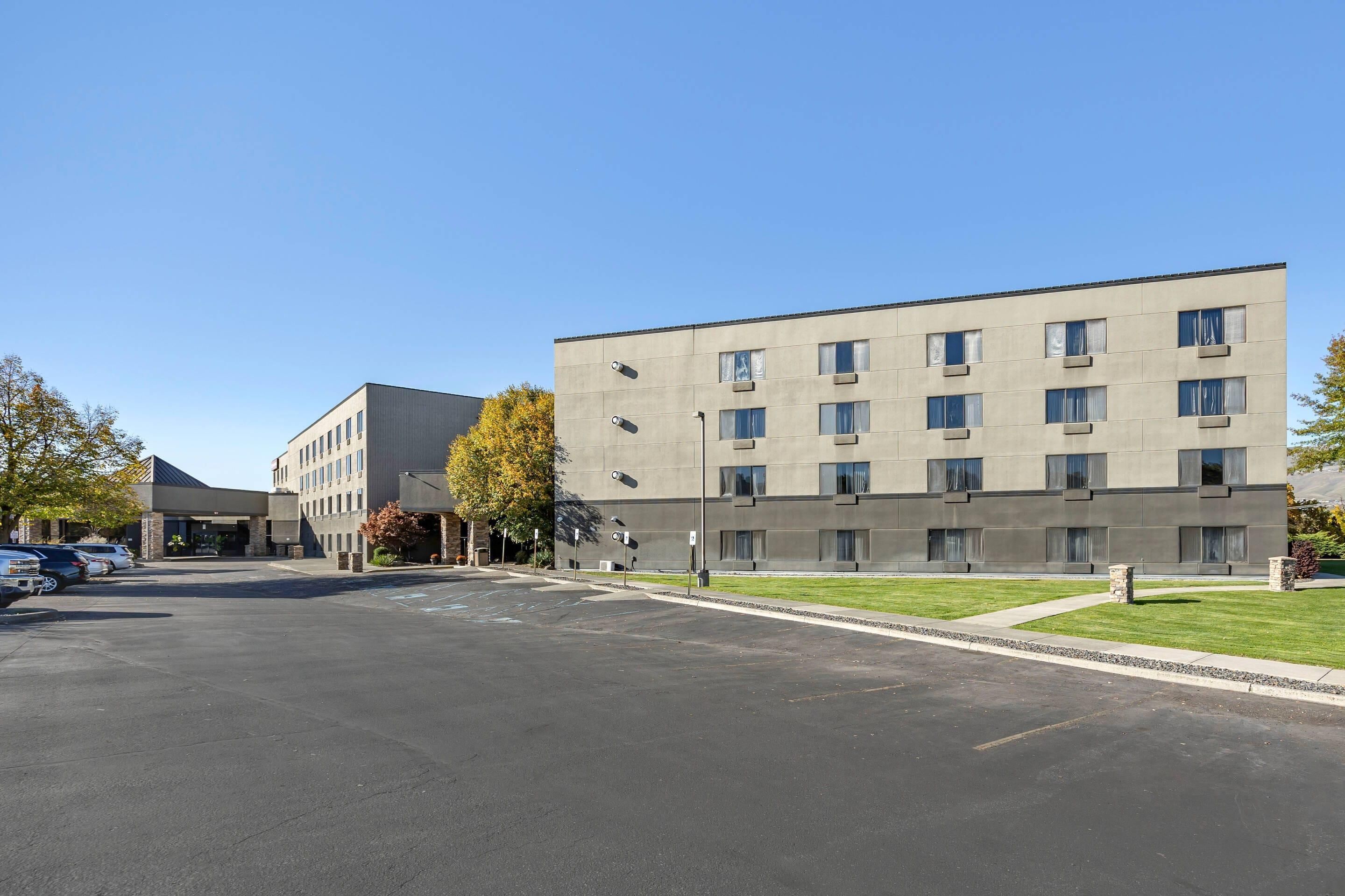 A multi-story hotel with a parking lot in front.