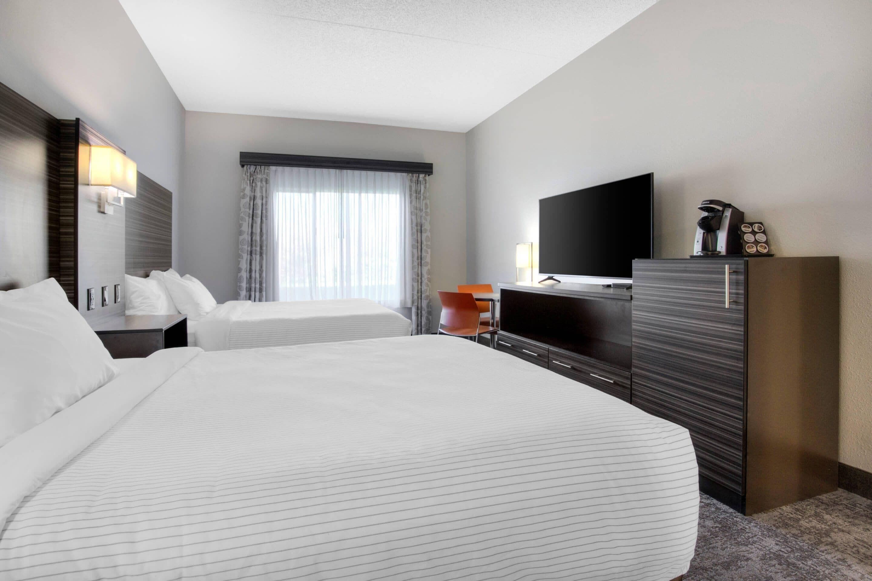 A hotel room with two beds, a TV, a desk, and a wardrobe.