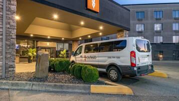 Un furgone bianco parcheggiato di fronte a un hotel con facciata in pietra e un cartello sopra l'ingresso.