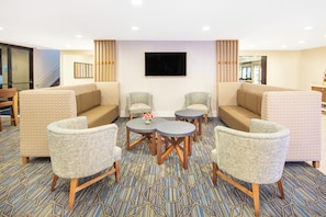 Un hall d'hôtel avec des canapés et des fauteuils aux motifs variés, ainsi qu'une table basse centrale.