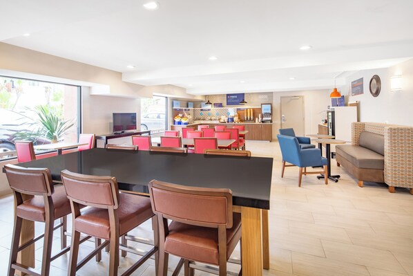 A modern dining area with a large table, bar stools, and a seating area with sofas and chairs.