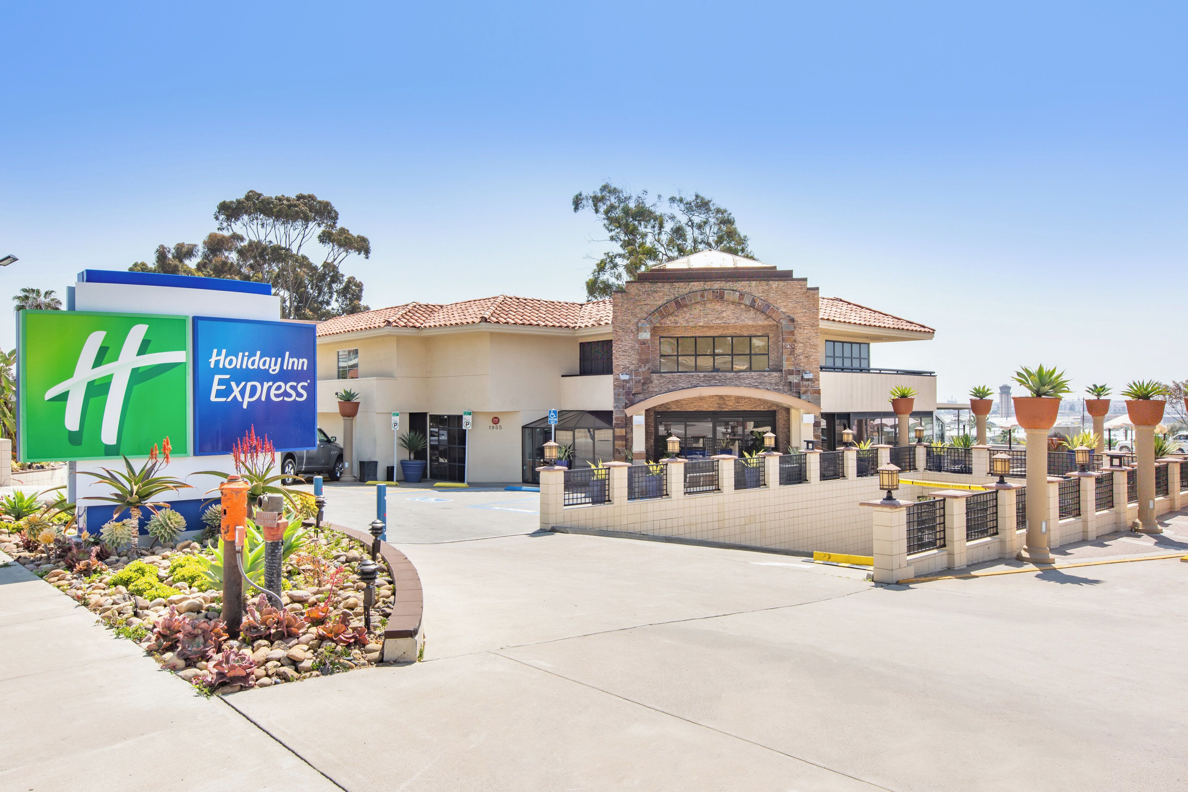 A Holiday Inn Express hotel with a clear entrance, a parking lot, and a landscaped area with plants.