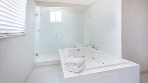 Une salle de bain moderne avec une grande baignoire, une douche à l’italienne et une petite fenêtre.
