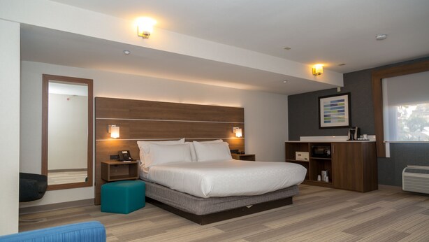 Une chambre d’hôtel moderne avec un grand lit, des tables de chevet, un bureau et une armoire.