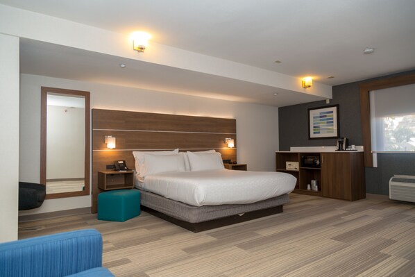 Une chambre d’hôtel moderne avec un grand lit, des tables de chevet, un bureau et une armoire.