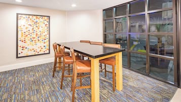 A conference room with a long table, chairs, a patterned carpet, and a large window with reflections.