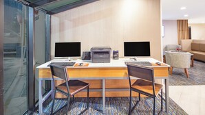 Une chambre d’hôtel équipée d’un bureau, de deux écrans d’ordinateur, d’une imprimante et d’une chaise.