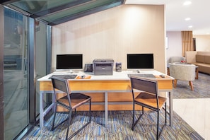 Une chambre d’hôtel équipée d’un bureau, de deux écrans d’ordinateur, d’une imprimante et d’une chaise.