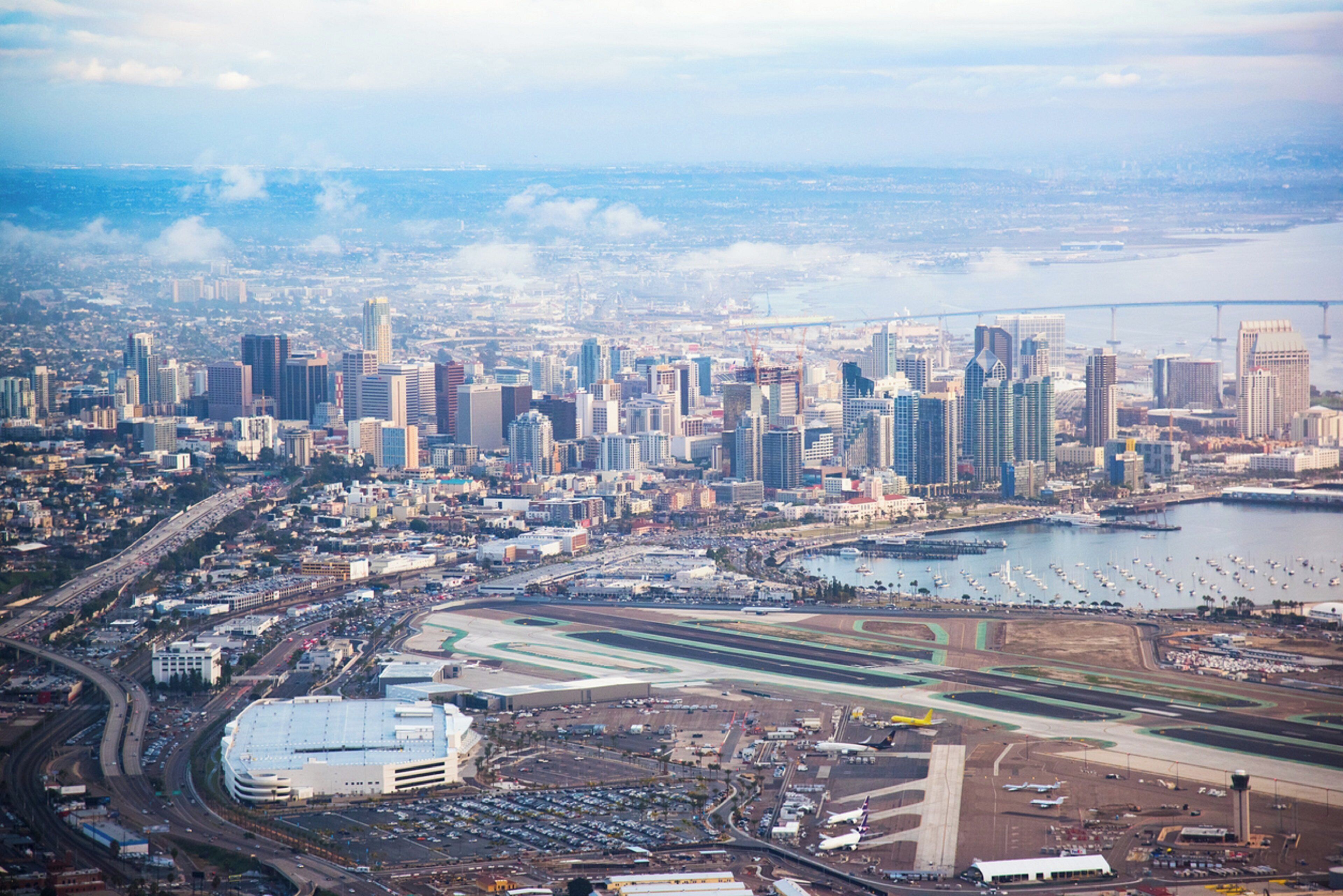 A cityscape with a prominent airport and a bridge in the distance.
