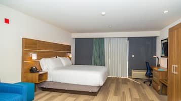 A hotel room with a bed, a desk, a chair, a TV, and a wardrobe.