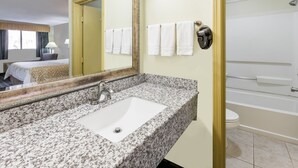 A hotel bathroom with a granite sink, a large mirror, a toilet, and a bathtub. - Days Inn by Wyndham Kent - Akron (Kent)
