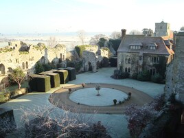 Un patio con arquitectura medieval, incluyendo muros de piedra y un jardín circular.
