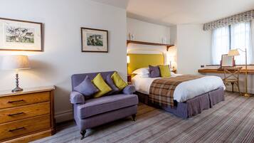 Una habitación de hotel con cama, sofá, escritorio y dos lámparas.
