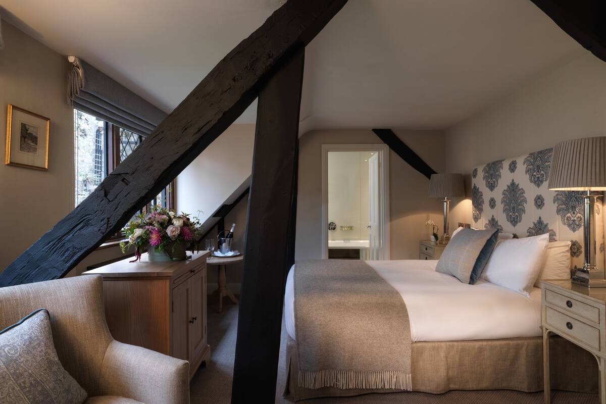 A bedroom with a large bed, a chair, a dresser, and a window with a view of the outside.