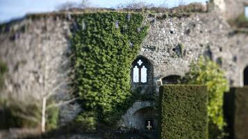 Un edificio de piedra con muros cubiertos de hiedra y una pequeña ventana arqueada.