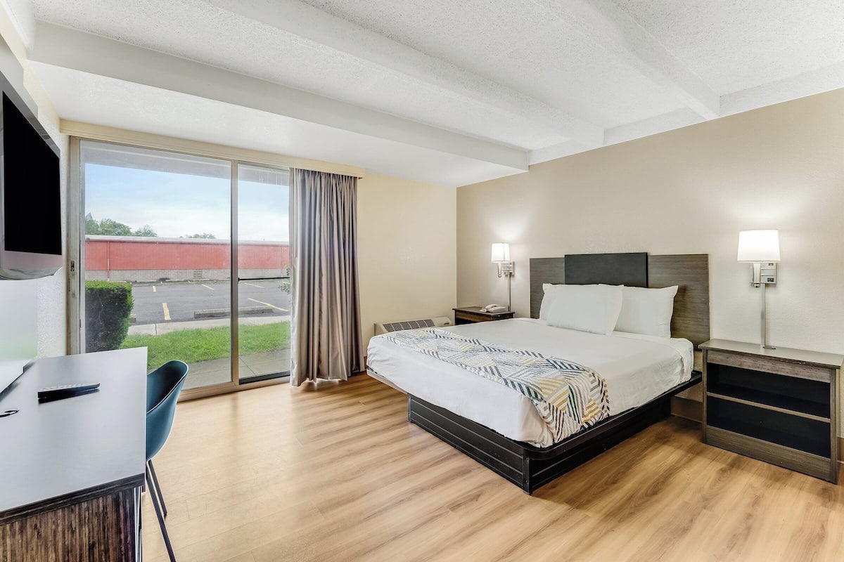 A hotel room with a bed, bedside tables, a desk, and a chair.