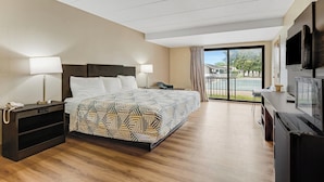 A modern hotel room with a large bed, bedside lamps, a flat-screen TV, and a balcony with a view.