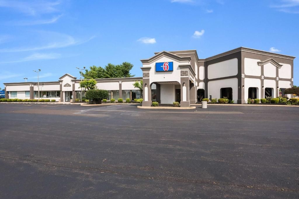 Un hôtel doté d’un grand parking et d’une entrée principale signalée par une enseigne bleue.