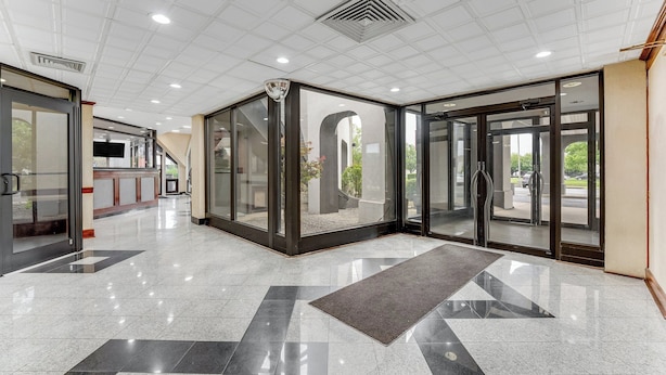 A modern lobby with a glass partition, a reception desk, and a clear view of the outdoors.