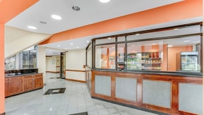 A hotel lobby with a reception desk, a wooden counter, and a glass display case.