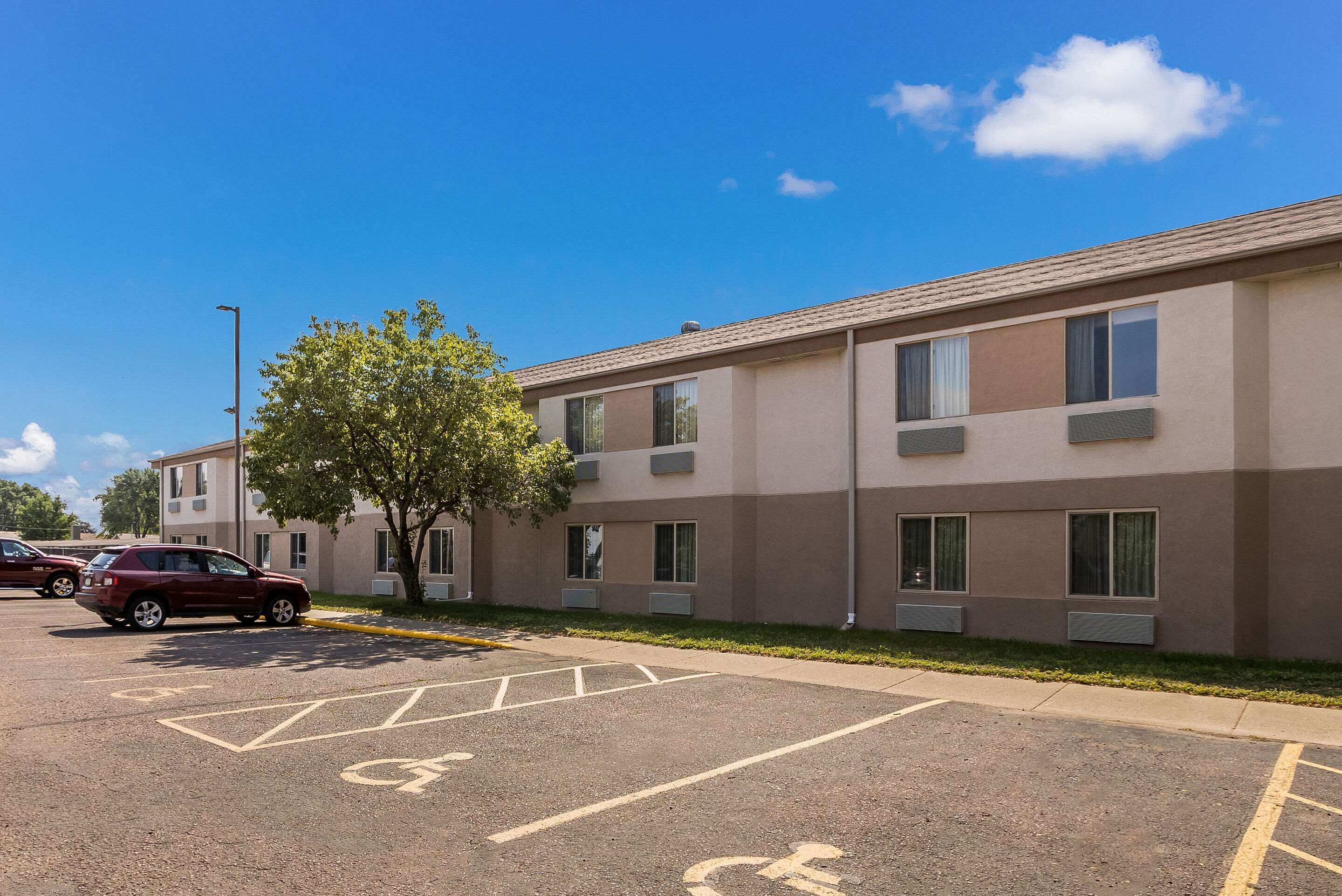 A parking lot with marked handicapped spaces and a building with multiple windows and air conditioning units.