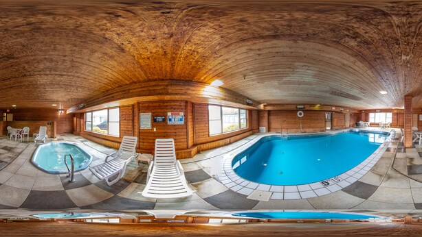 Una amplia piscina interior con dos zonas separadas, rodeada de paredes de madera y un suelo con estampado de cuadros.