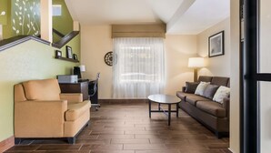 Una sala de estar con un sofá, una mesa de centro, una lámpara y una escalera con un muro decorativo.