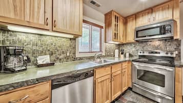 A modern kitchen with wooden cabinets, a stainless steel dishwasher, a built-in microwave, and a gas stove.