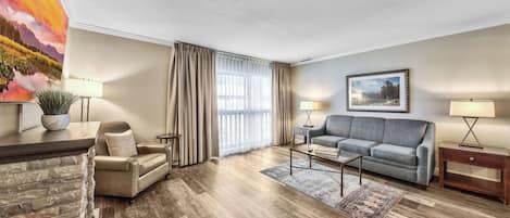 Una sala de estar con sofá, sillón, mesa de centro y un cuadro en la pared.