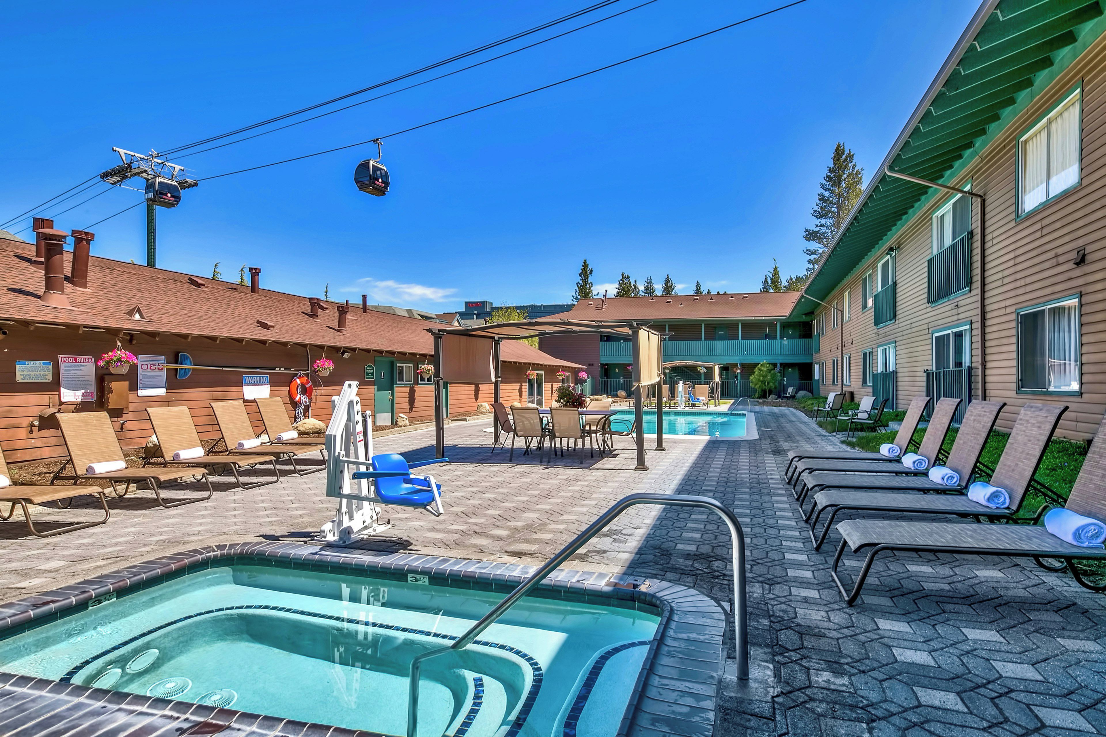 A pool area with lounge chairs, a pool, and a building with a green roof.