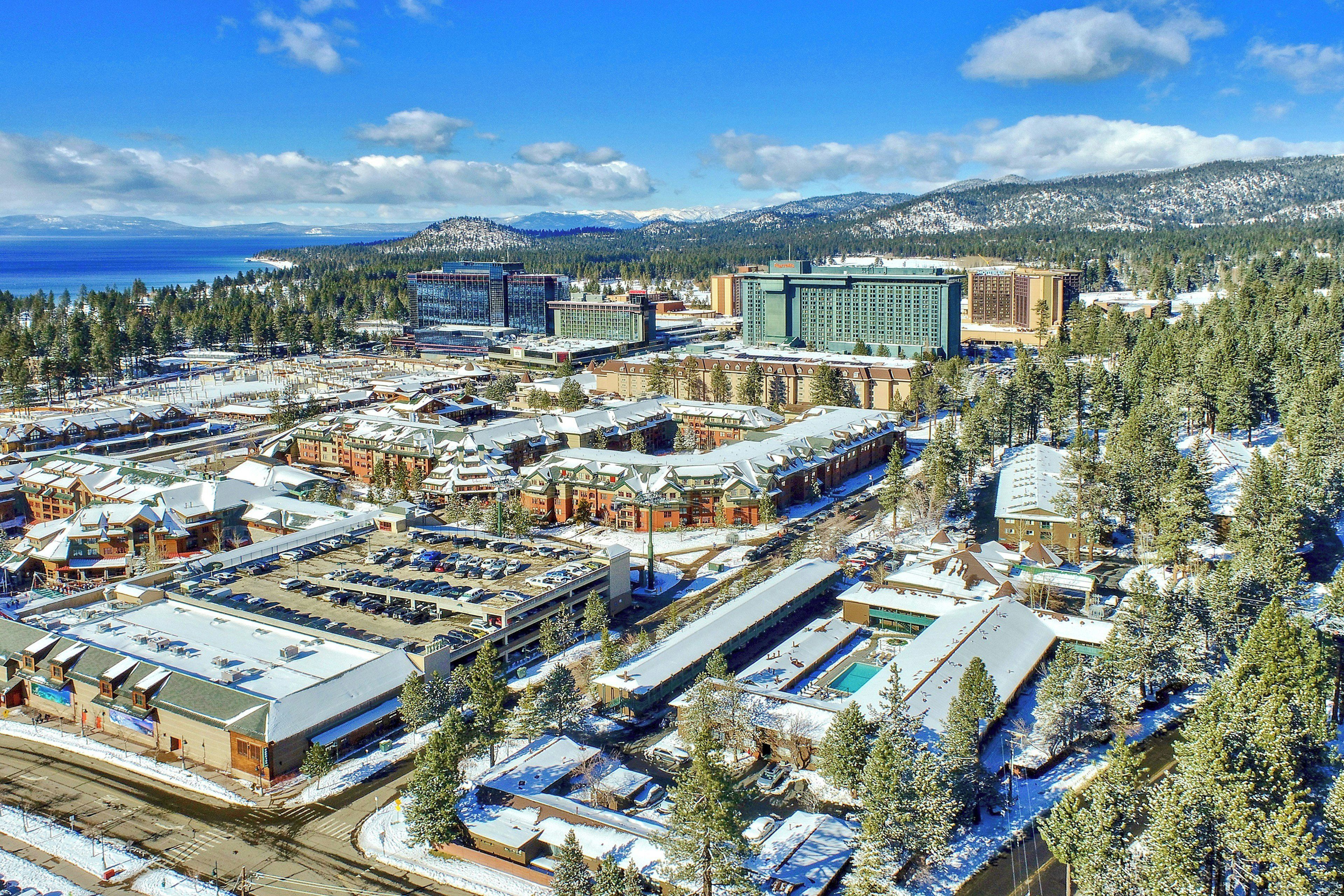 A snow-covered urban area with multiple buildings, including a hotel with a large parking lot.